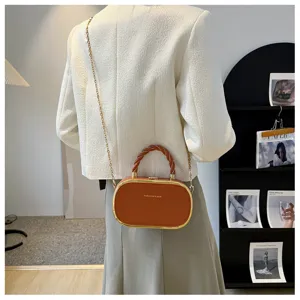 Sac bandoulière ovale chic avec poignée tressée, chaîne dorée et détails métalliques.