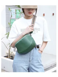 Green genuine leather saddle bag with striped strap, stylish chest bag detail view for women.