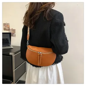Stylish brown leather crescent saddle crossbody bag with wide strap and dual zippers.