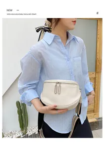 Detail view of the white leather saddle chest bag, showing texture, double zippers.