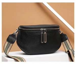 Detail view of black genuine leather saddle bag with wide striped strap and double metal zippers.