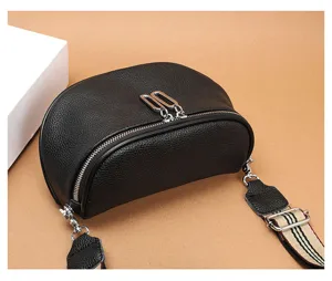 Close-up detail shot of black leather saddle chest bag, showing silver hardware and strap.