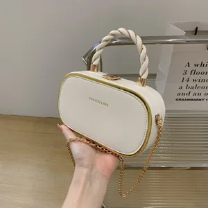 Élégant sac à main rigide blanc avec poignée torsadée et bandoulière chaîne dorée.