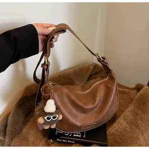 Bruine retro leren schoudertas detail, zachte textuur, metalen rits en schattige pluche hanger dames.
