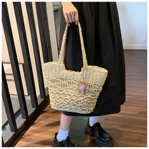 Detailed view of woven straw beach tote bag with cute purple flower pendant and spacious design.