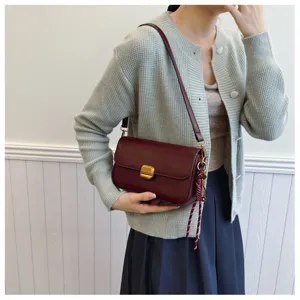 Élégant sac à bandoulière bordeaux avec fermoir doré, idéal pour un look chic et quotidien.