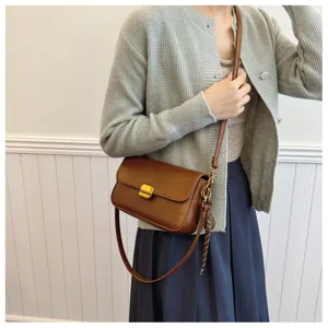 Sac bandoulière rétro marron en cuir PU pour femme avec serrure métal et foulard décoratif.