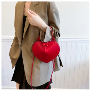 Dettaglio borsa a tracolla cuore rosso, finitura lucida e design del manico elegante.