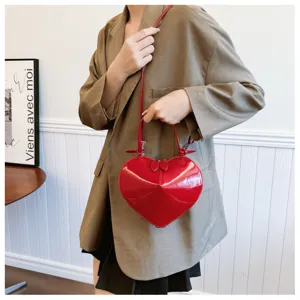 Dettaglio borsa a mano rossa lucida a forma di cuore con finitura in pelle verniciata elegante.