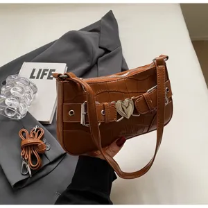 Vue rapprochée du sac porté épaule marron texture crocodile avec boucle cœur et détail lanière.