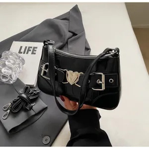 Détail de sac à épaule noir effet croco, avec boucle cœur en métal et design élégant.