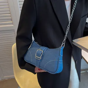 Dettaglio borsa a spalla in denim blu con fibbia argentata e catena, stile elegante.