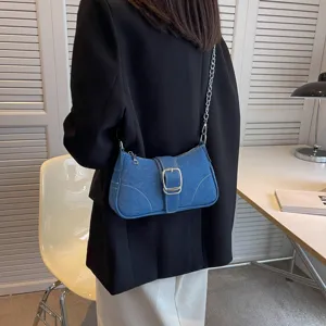 Vista dettagliata della borsa a tracolla in denim blu con catena argentata e fibbia.