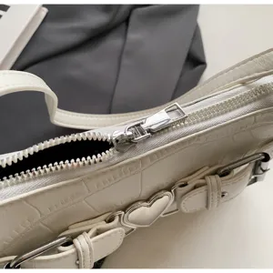 Détail du sac à épaule blanc effet croco, vue rapprochée sur la fermeture éclair et la boucle.