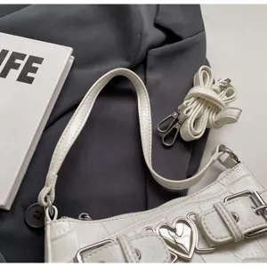 Gros plan détaillé du sac à épaule texturé blanc avec boucle cœur en métal chic.
