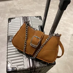 Dettaglio borsa a spalla marrone con catena metallica elegante e fibbia di tendenza.