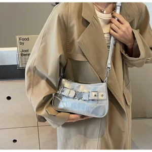 Détail de sac porté épaule argenté avec boucle cœur métallique et texture crocodile.