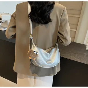 Detailopname van een stijlvolle zilveren metallic schoudertas met harige pluizige bedel.
