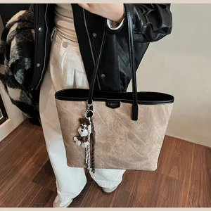 Detailansicht der eleganten PU Leder Tasche mit kontrastierenden Griffen und charmantem Anhänger.