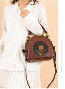 Detailansicht der braunen Lederhandtasche mit kunstvollem Hirsch-Relief und edlen Bambusgriffen.