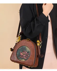 Nahaufnahme der braunen Ledertasche mit filigraner Lotus-Prägung und Bambus-Griffdetails.