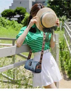 Vue détaillée en extérieur d'un sac porté épaule élégant en cuir bleu avec large bandoulière.
