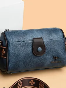 Sac à bandoulière oreiller en cuir texturé bleu avec sangle marron et boucle chic.