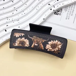 Detail view of the retro western style hair claw clip featuring cow and sunflower graphic pattern.