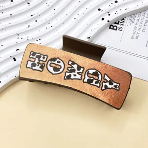 Western style leather hair claw clip with cow print and honey letter design for women.