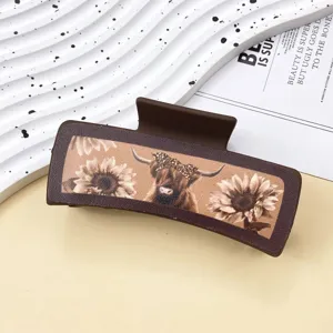 Brown leather hair claw clip featuring a western highland cow and sunflower pattern design.