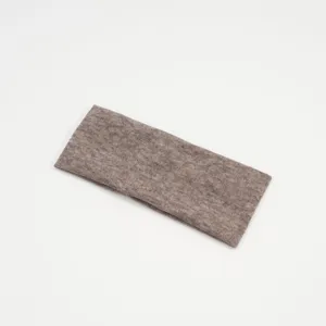 Dettaglio della fascia per capelli in maglia marrone, tessuto elastico e design a coste.