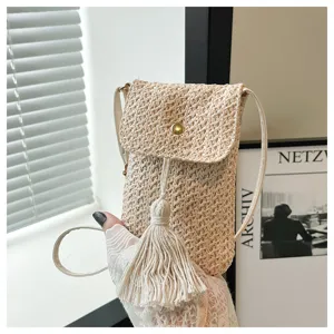 Detail shot of summer straw woven mini crossbody bag with tassel and magnetic clasp.