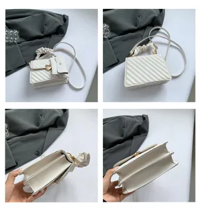 Close-up details of the elegant white crossbody bag with ruched handle and heart clasp.