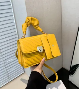 Stylish yellow crossbody bag with pleated handle, heart metal clasp and side pouch detail.