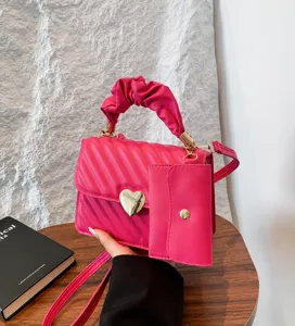 Detail view of pink PU leather crossbody bag with heart clasp, ruched handle, and pouch.