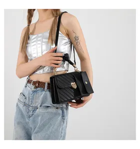 Close-up detail of a chic black quilted crossbody bag featuring a golden heart lock and chain handle.