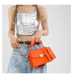 Detailed shot of trendy orange crossbody bag with chic heart-shaped metal buckle and small pouch.