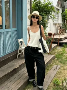 Photo de détail de mode lifestyle en extérieur avec haut en tricot blanc et jean noir.