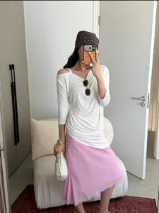 Detail shot of a stylish pink draped linen-blend fishtail skirt worn with an elegant top.