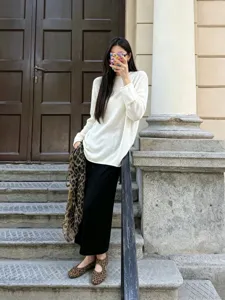 Casual white knit sweater detail scene, loose long sleeve apparel design on outdoor steps.