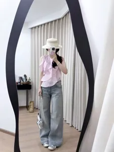 Elegante completo da donna con top rosa senza maniche e jeans ampi dal lavaggio chiaro.