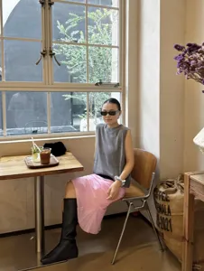 Detail view of the elegant pink linen blend bias cut fishtail midi skirt worn in a chic cafe.