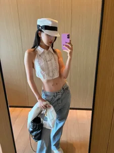 Detailed view of stylish white halter crop shirt paired with low-rise jeans and chic accessories.