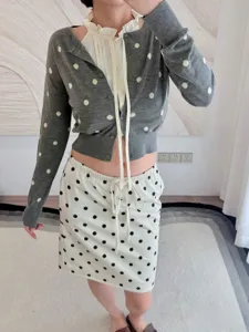 Detailed shot of grey polka dot knit cardigan paired with ruffled blouse for women fashion.