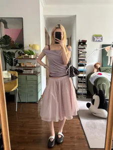 Detailansicht eines rosafarbenen Tüll-Plissee-Rocks im Zimmer mit lässigem Outfit.