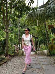 Outdoor lifestyle detail shot showcasing a stylish pink bias-cut mermaid skirt in jungle.