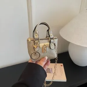 Mini metallic handbag charm with chain strap and padlock detail, closeup product detail view.