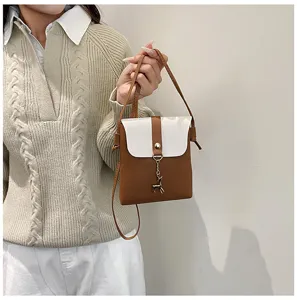 Close up detail view of mini crossbody phone bag in brown and white with cute deer charm.