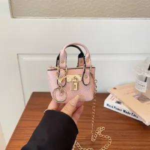 Charming pink mini handbag with gold chain strap and lock detail, stylish accessory for women.
