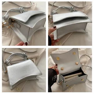 Detailed view of metallic silver women shoulder bag with knot handle and curved bottom design.
